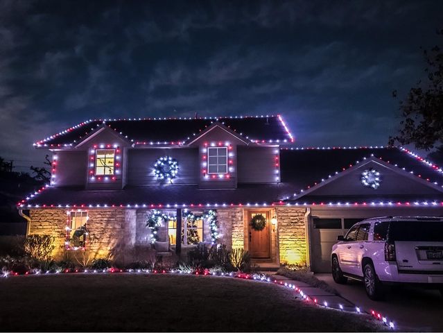 Brick home with white roofline lights and lit trees